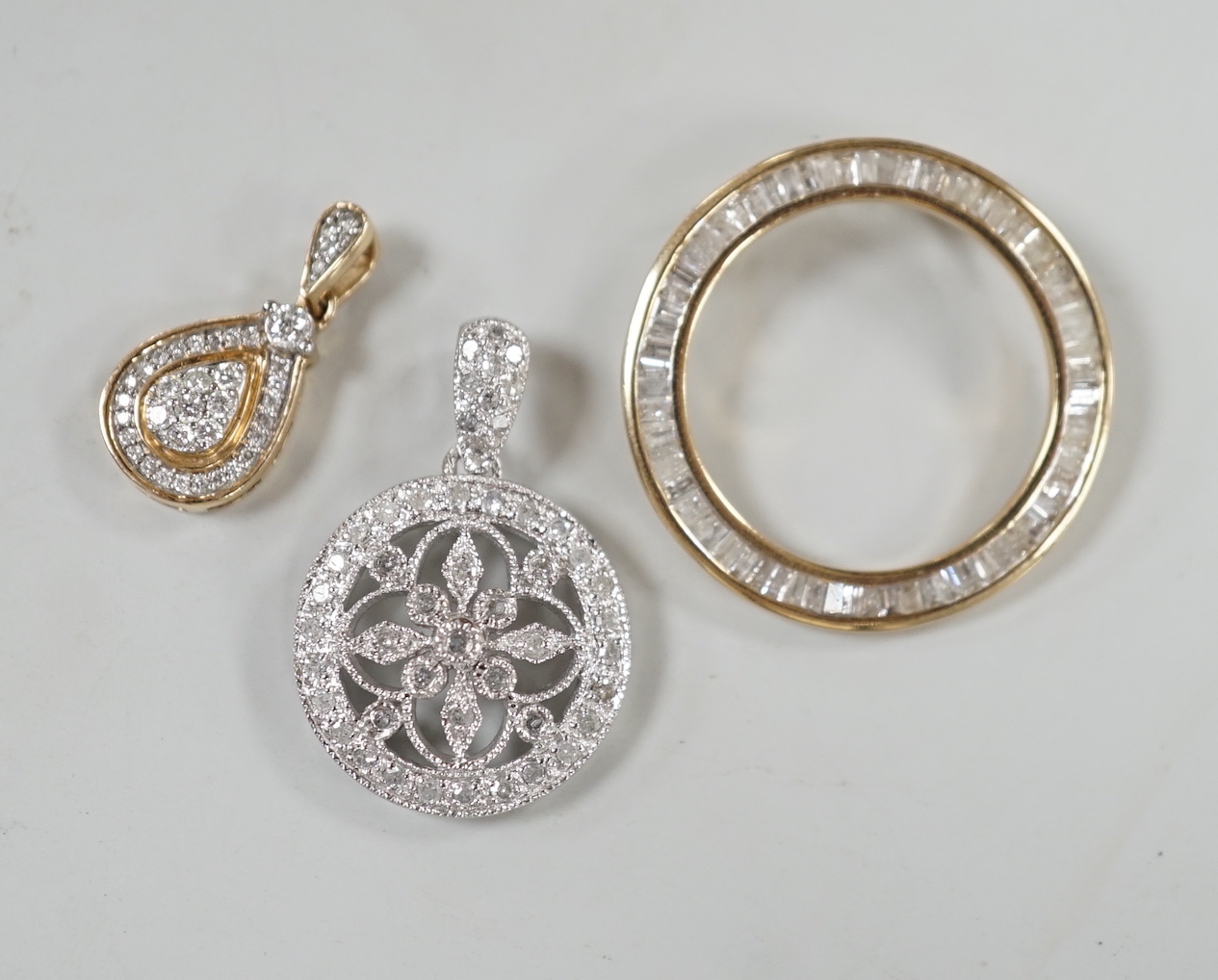 A modern 9ct white gold and diamond cluster set drop circular pendant, diameter 17mm, a small 9ct gold and diamond chip set pear shaped drop pendant and a 9ct gold and baguette cut diamond cluster set circular open work